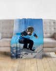 Personalized pet blanket with a pug's head on a snowboarder's body, draped over a gray sofa.