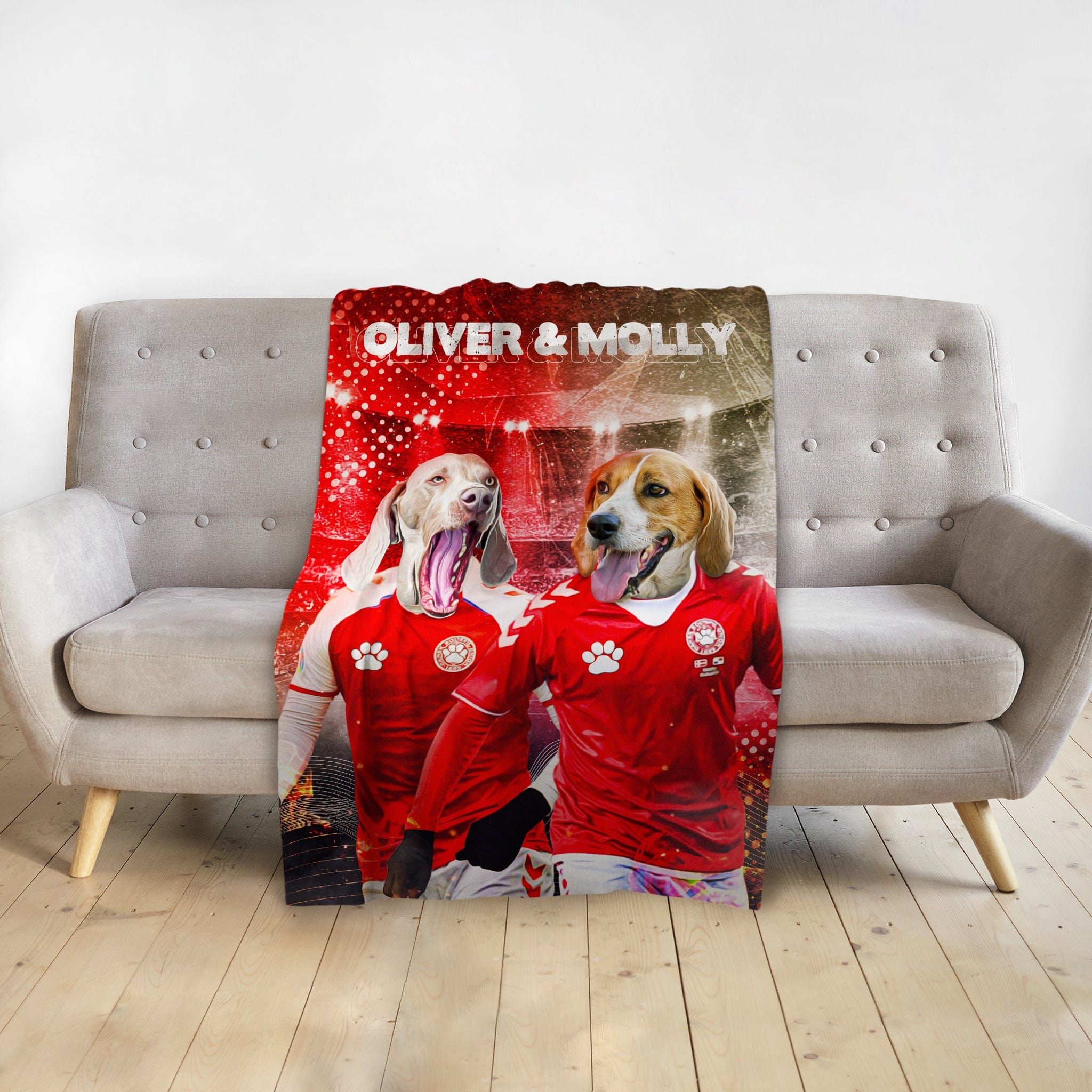 Personalized pet blanket with two dogs in red soccer jerseys, named Oliver & Molly, on a gray sofa.