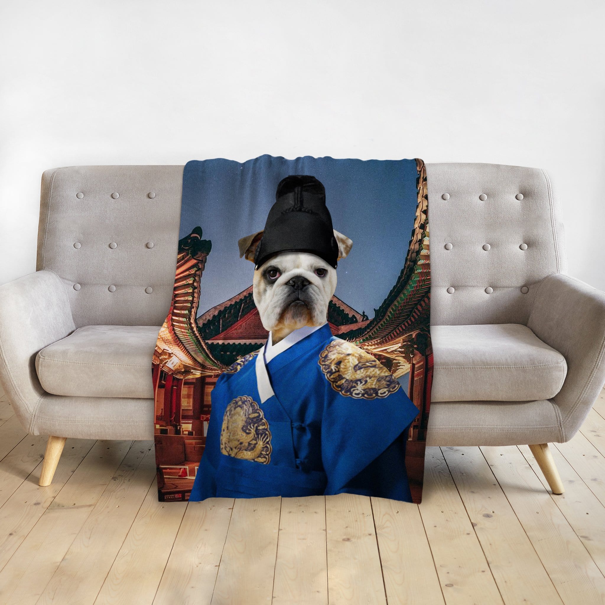 Custom pet blanket with a bulldog in a blue Asian Emperor portrait, draped over a gray couch.