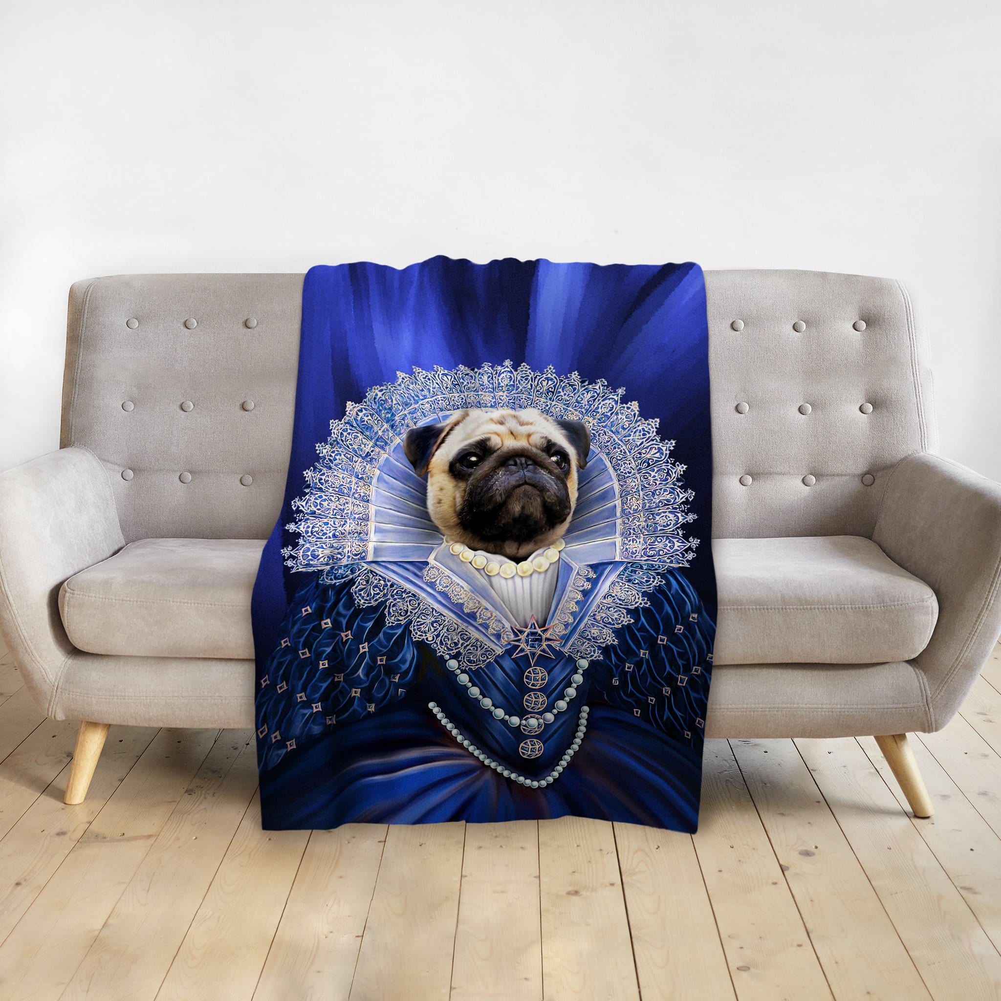 Personalized pet blanket with a pug in a royal blue renaissance portrait on a gray sofa.