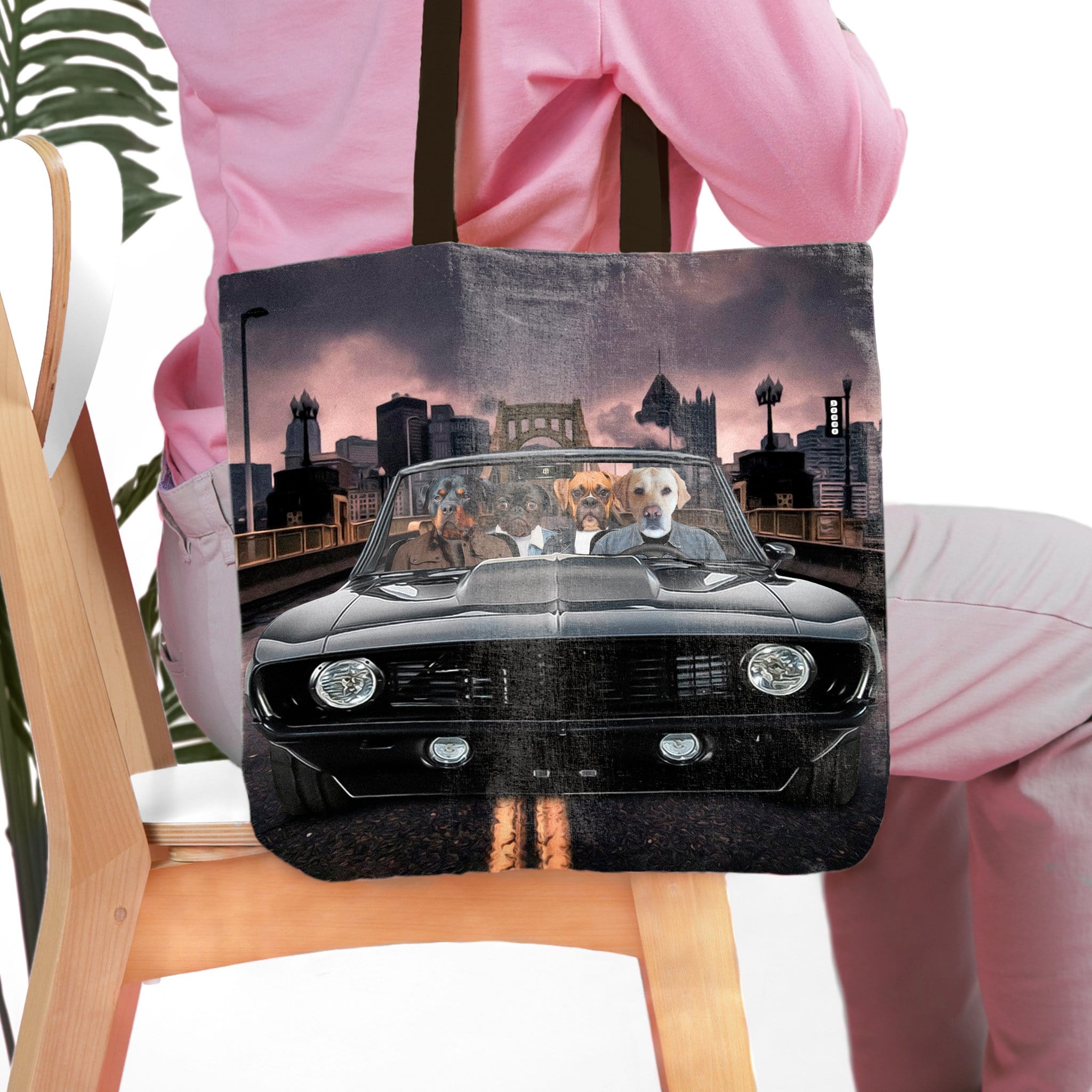 Personalized black tote bag with four dog portraits in a classic car, city background.