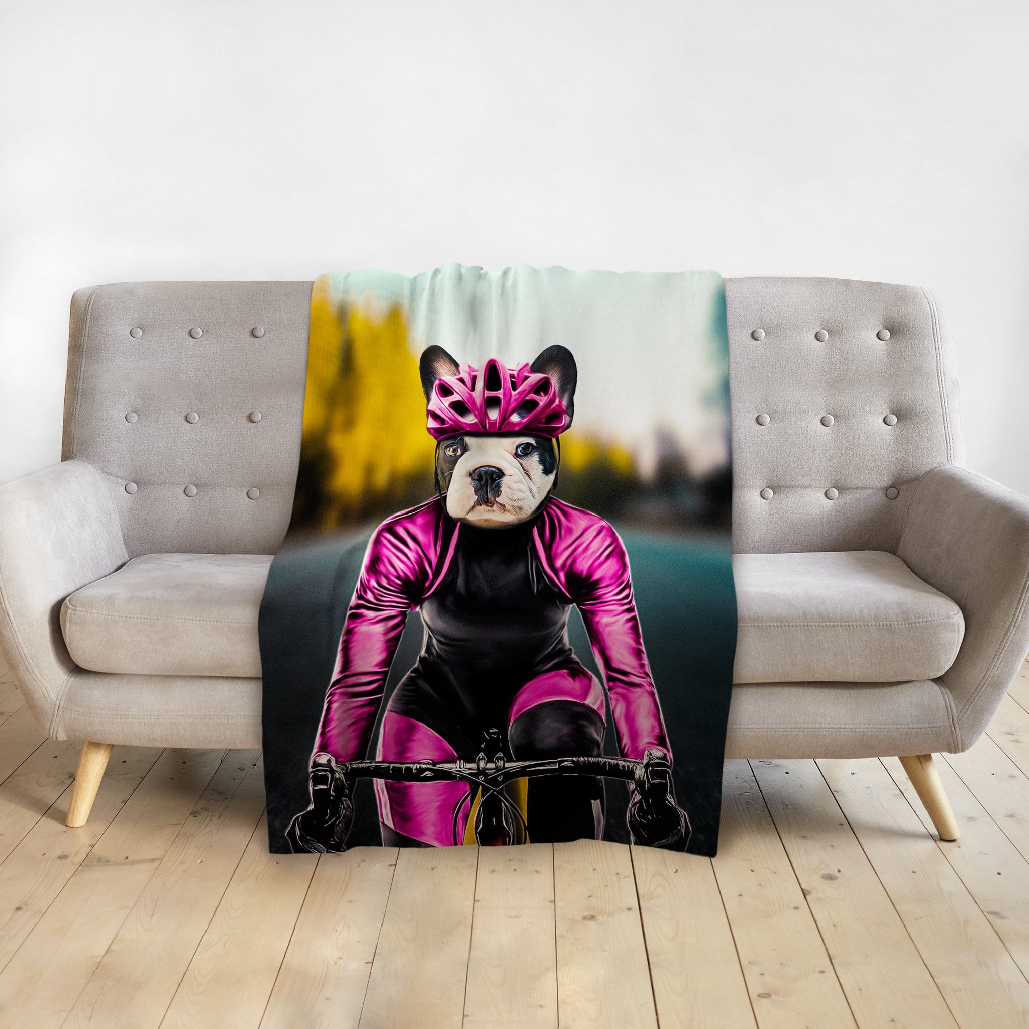 Personalized pet blanket with a French Bulldog in a pink cycling outfit on a gray sofa.