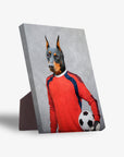 Doberman pet portrait on a standing canvas, dressed as a soccer goalie in a red jersey, holding a ball.