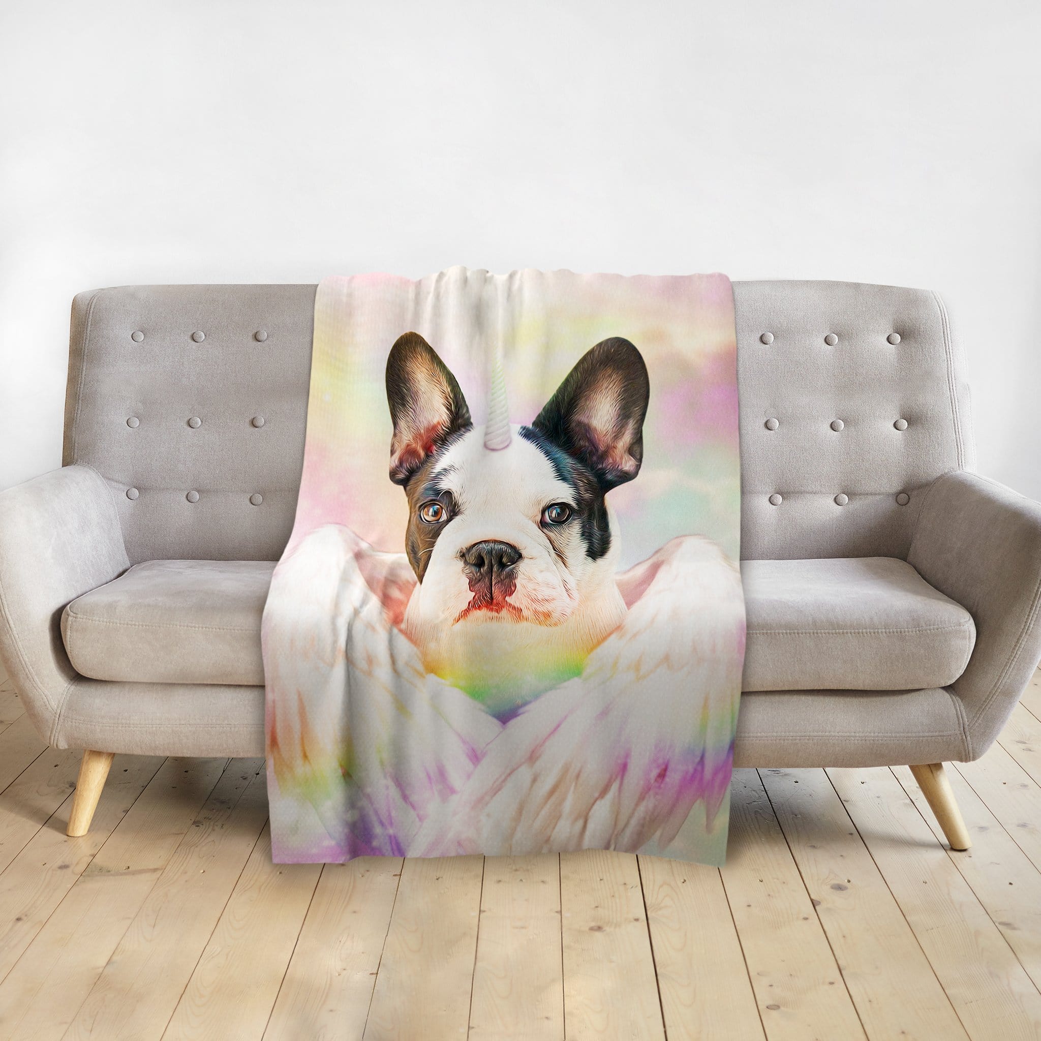 Personalized pet blanket with a French Bulldog unicorn portrait on a pastel background, draped over a gray sofa.