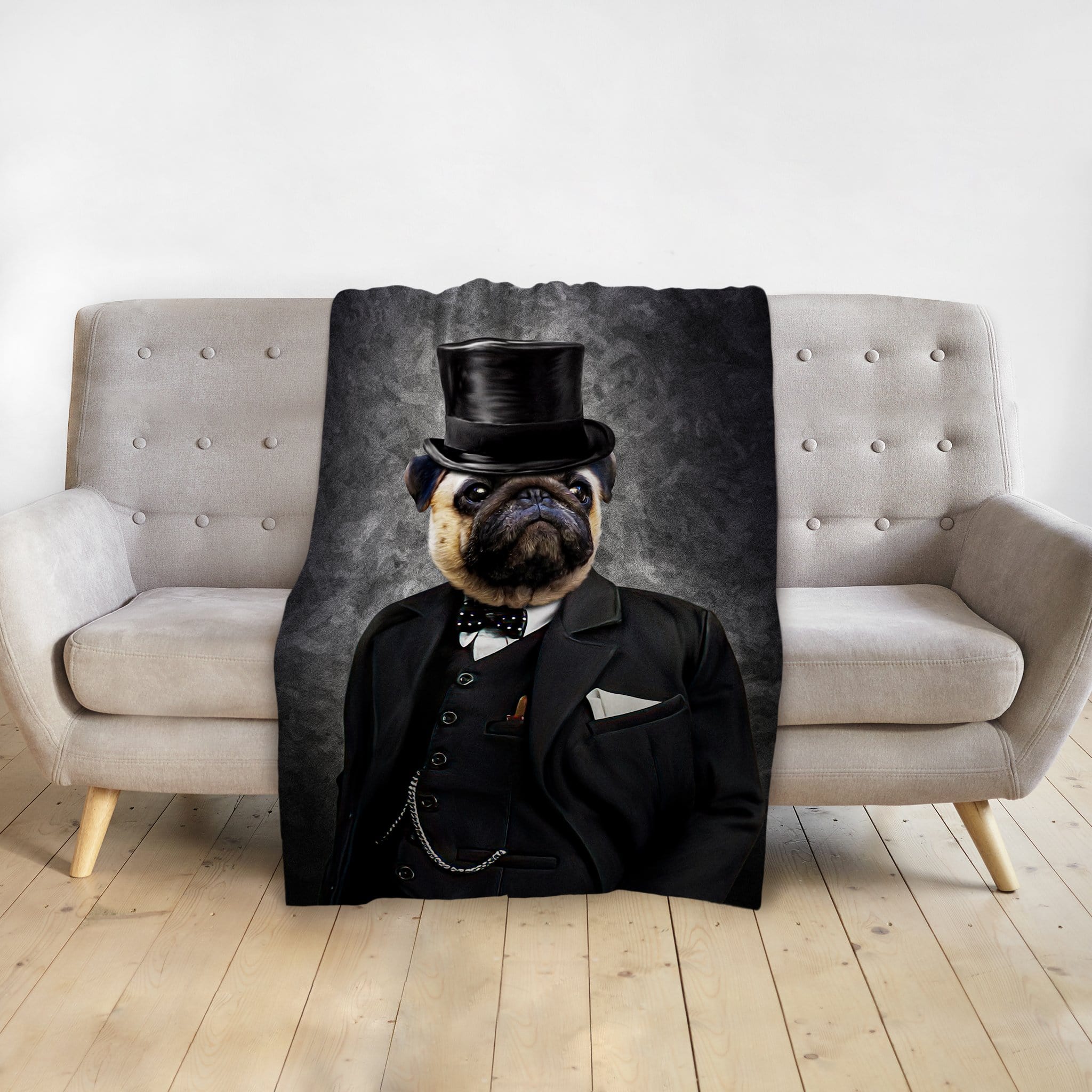 Personalized pet blanket with a pug in a black top hat and suit, draped over a grey sofa.