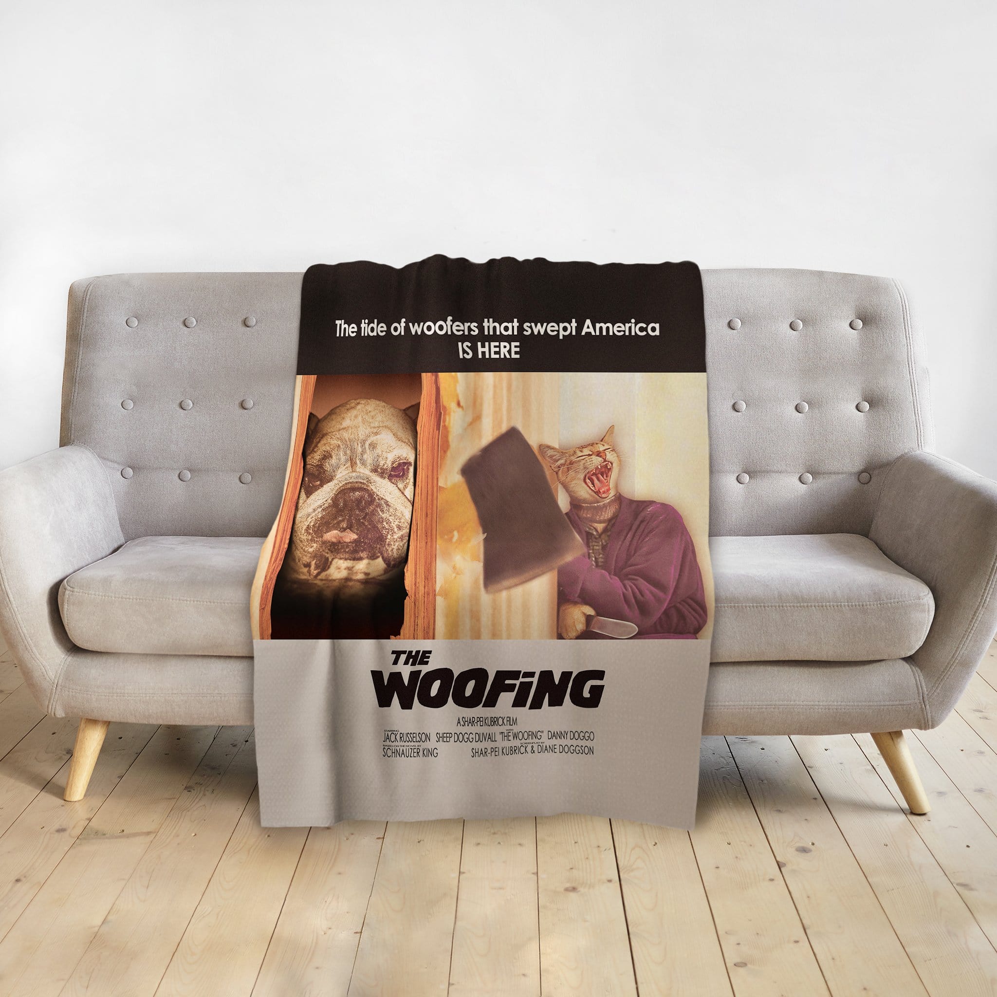 Personalized "The Woofing" blanket with custom pet portraits of a bulldog and a cat, draped on a gray sofa.